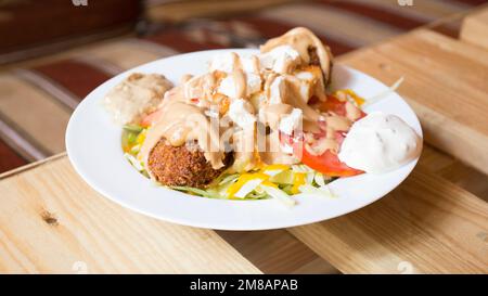 Plat combiné de falafel avec légumes. Faláfel ou falafel​ est une croquette de pois chiches ou de fèves. Il est généralement consommé au Moyen-Orient. Banque D'Images