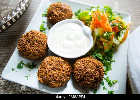 Plat combiné de falafel avec légumes. Faláfel ou falafel​ est une croquette de pois chiches ou de fèves. Il est généralement consommé au Moyen-Orient. Banque D'Images