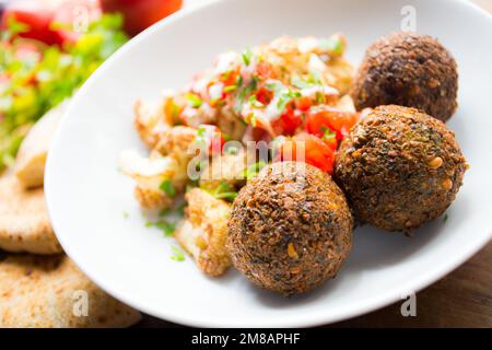 Plat combiné de falafel avec légumes. Faláfel ou falafel​ est une croquette de pois chiches ou de fèves. Il est généralement consommé au Moyen-Orient. Banque D'Images