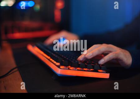 Gros plan des mains du joueur sur le clavier, en appuyant sur les boutons, en jouant à des jeux vidéo en ligne. Hacker utilise le clavier, secoue les boutons avec les doigts pour craquer le mot de passe. Sécurité Internet, cyberattaque. Couleur néon Banque D'Images