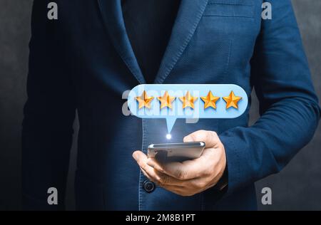 Client homme d'affaires qui donne cinq étoiles au téléphone.concept d'expériences client. Happy client utilisant un smartphone pour soumettre une évaluation cinq étoiles. P Banque D'Images