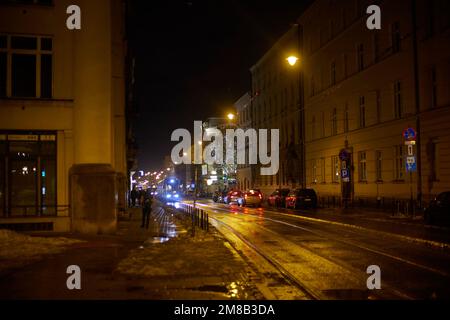 Trafic sur la route de nuit, le tramway traverse les bâtiments de Cracovie, en Pologne. Banque D'Images