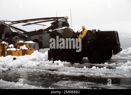 Un chariot élévateur est utilisé pour dégager la neige autour d'un hélicoptère CH-46E Sea Knight du Marine Medium Helicopter Squadron 166 (HMM-166) sur le pont de vol du navire d'atterrissage du quai USS JUNEAU (LPD-10). Le JUNEAU fournit un soutien au personnel militaire et civil qui travaille à nettoyer le pétrole renversé lorsque le pétrolier EXXON VALDEZ a échoué dans le détroit du Prince William sur 24 mars. Base: Valdez État: Alaska (AK) pays: Etats-Unis d'Amérique (USA) Banque D'Images