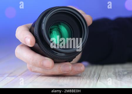 50mm objectif à portée de main sur la table et sur fond bleu Banque D'Images