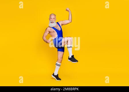 Portrait pleine grandeur d'une personne sportive ravie et surjoyeuse qui élève la réussite des poings, isolée sur fond jaune Banque D'Images