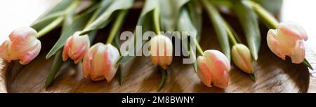 un bouquet de tulipes délicates - un cadeau pour une femme - repose sur un plateau en bois Banque D'Images