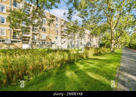 un complexe d'appartements avec des arbres et de l'herbe à l'avant - image est prise de la rue, en regardant vers la route Banque D'Images