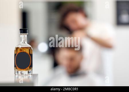 bouteille d'huile essentielle sur fond flou de l'homme au salon de coiffure. Banque D'Images