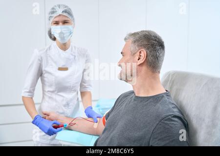 Une infirmière en salle de manipulation stérile prélève l'échantillon de sang du patient Banque D'Images