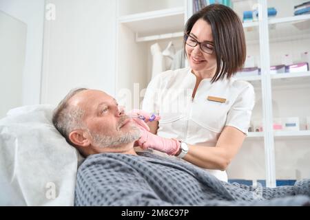 Le patient âgé reçoit des injections de collagène dans une clinique de médecine esthétique Banque D'Images