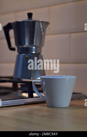 Moka pot sur la cuisinière avec une tasse de café sur le plan de travail Banque D'Images