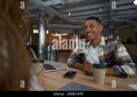 Homme souriant écoutant attentivement sa collègue féminine Banque D'Images