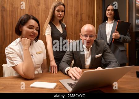 Les femmes se sont rassemblées autour d'un homme dans un costume d'affaires Banque D'Images