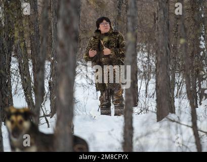 (230113) -- GENHE, 13 janv. 2023 (Xinhua) -- Juele cherche son renne dans la forêt de Jinhe près de la ville de Genhe, région autonome de l'intérieur de la Mongolie, au nord de la Chine, 12 janv. 2023. Tous les deux ou trois jours, Juele Bulituotian se dirige vers la forêt de Jinhe à environ 80 kilomètres de la ville de Genhe. C'est là que le jeune Aoluguya Ewenki de 39 ans, portant un manteau de fourrure traditionnel, trouvera son renne fourrager. Au lieu de garder les rennes dans une grange, les éleveurs Ewenki laissent les animaux vivre dans la forêt et les vérifient tous les deux jours. Juele possède plus de 60 rennes. Il appellera sa rétreince Banque D'Images