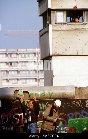 Un homme ouest-allemand étudie son morceau du mur de Berlin tandis qu'un autre affiche avec jubilé son souvenir aux spectateurs. Une partie du mur a déjà été démolie à la Potsdamer Platz. Base: Berlin pays: Allemagne / Allemagne (DEU) Banque D'Images