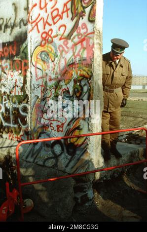 Un policier est-allemand regarde un petit arbre de Noël ornant le côté ouest-allemand du mur de Berlin. La garde est debout à l'ouverture nouvellement créée dans le mur de Berlin à Potsdamer Platz. Base: Berlin pays: Allemagne / Allemagne (DEU) Banque D'Images