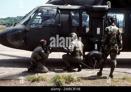 PERSONNEL SGT. Jim Kemplin, à gauche, de l'Escadron de l'audiovisuel 1352nd, magnétope le chef d'équipage d'a Co A, 1st BN., 228th Aviation Regt., UH-60A hélicoptère Black Hawk (Blackhawk) qui signe du carburant pendant les opérations à l'appui de l'opération Just cause. Objet opération/série: BASE POUR CAUSE JUSTE: Base aérienne de Howard pays: Panama (PAN) Banque D'Images