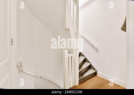 un escalier dans une maison avec des murs blancs et du parquet les escaliers sont faits jusqu'à un niveau supérieur Banque D'Images