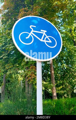 Panneau de signalisation bleu et blanc indiquant l'itinéraire du vélo, grand panneau de signalisation circulaire sur la route. Banque D'Images