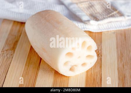 Racine de lotus blanc (renkon) sur la planche à découper en bois dans la cuisine de près. Banque D'Images