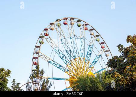 Grande roue de carnaval dans le parc d'attractions en été tournant contre le ciel bleu. Banque D'Images