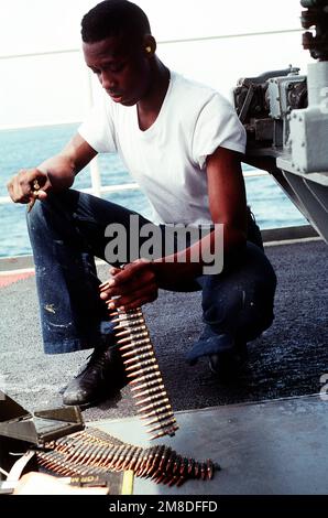 Un membre de l'équipage à bord du navire de commandement amphibie USS BLUE RIDGE (LCC-19) place 7,62mm cartouches pour une mitrailleuse M-60 dans une ceinture de munitions lors des qualifications pour armes légères. La BLUE RIDGE fait partie des États-Unis Des navires de la Marine ont été déployés dans la région à l'appui de l'opération Desert Shield. Sujet opération/série: BOUCLIER DU DÉSERT pays: Inconnu Banque D'Images