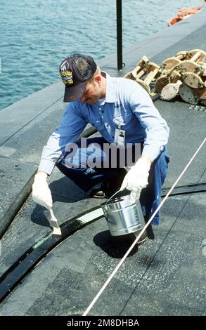 Un homme d'équipage peint la piste de sécurité sur le pont du sous-marin de missiles stratégiques à propulsion nucléaire USS NEVADA (SSBN 733) tandis que le navire est au chantier naval de long Beach pour l'entretien. Base: Long Beach État: Californie (CA) pays: Etats-Unis d'Amérique (USA) Banque D'Images