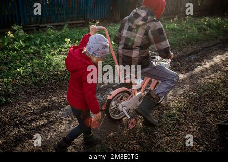 Une fille pousse un vélo avec son frère aîné. Enfants d'immigrants Banque D'Images