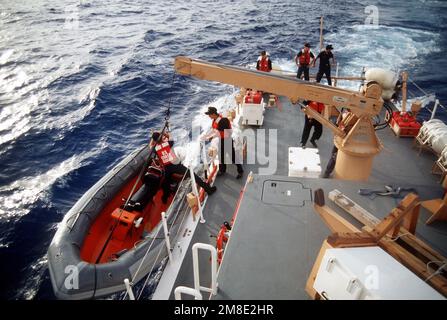 Les membres de équipage à bord de la Garde côtière Grande embarcation de patrouille USCGC KISKA (WPB-1336) utilisent une grue pour abaisser un bateau gonflable à coque rigide dans l'eau pendant l'opération Steel Box. Le KISKA est en place pour assurer la sécurité lors de la livraison de munitions chimiques à l'atoll Johnston. Objet opération/série: BOÎTE EN ACIER pays: Johnston Atoll Banque D'Images