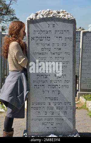 Une jeune femme juive orthodoxe dit une prière personnelle à la tête de Chaya Mushka Schneerson, l'épouse du Lubavitcher Rebbe. À Queens, New York. Banque D'Images