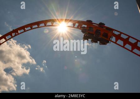 Les cavaliers sur la Thunderbolt à Coney Island ont tiré contre le soleil, le ciel et les nuages. À Brooklyn, New York. Banque D'Images