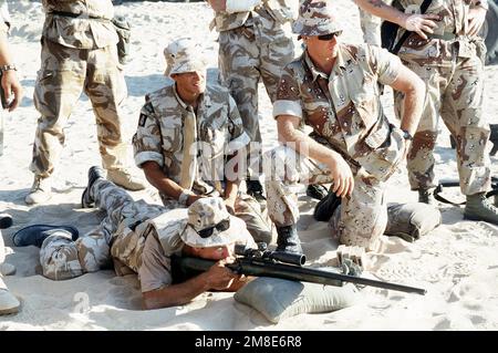 Des soldats britanniques des gardes-dragons de la Reine et des Marines du peloton 7th, 1st Force reconnaissance Company, observent l'un des soldats britanniques qui tire un fusil à fusil M-40A1 pendant que l'entraînement aux armes est mené à Abu Hydra Range pendant l'opération Desert Shield. Objet opération/série : BOUCLIER DU DÉSERT pays : Arabie saoudite (SAU) Banque D'Images