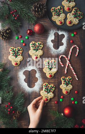 Main atteignant pour le biscuit de noël en forme de renne sur la table en bois. Banque D'Images