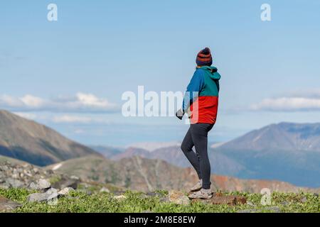 Femme debout dans une région alpine du nord du Canada pendant l'été. Porter des vêtements de randonnée avec de vastes montagnes en arrière-plan. Banque D'Images