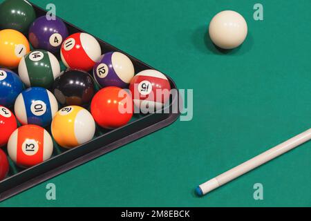 Boules de billard colorées avec des numéros avec des bâtons de repère et un rack sur une table bleue. Banque D'Images