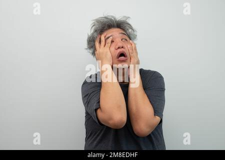 Portrait d'un homme furieux à cheveux gris hurlant, hurlant et faisant des gestes de peur avec les mains et le visage sur un arrière-plan isolé Banque D'Images
