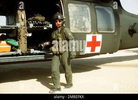 Le chef d'équipage d'un hélicoptère UH-60A Black Hawk (Blackhawk) de 45th Medical Company monte une civière repliée à bord de l'hélicoptère pendant l'opération Desert Shield. Objet opération/série : BOUCLIER DU DÉSERT pays : Arabie saoudite (SAU) Banque D'Images