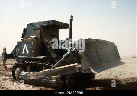 Un membre de Co. A, 299th Engineer BN., attaché au 3rd Engineer BN., 24th Infantry Division, a enfreint une berme menant en Iraq à l'aide d'un tracteur de terrassement blindé D-7G pendant l'opération Desert Storm. Objet opération/série : TEMPÊTE DANS LE DÉSERT pays : Arabie saoudite (SAU) Banque D'Images