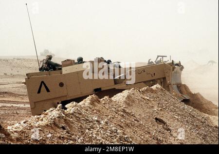 Un membre de Co. A, 299th Engineer BN., attaché au 3rd Engineer BN., 24th Infantry Division, viole un berme menant en Irak à l'aide d'un appareil de terrassement blindé M-9 ACE pendant l'opération Desert Storm. Objet opération/série : TEMPÊTE DANS LE DÉSERT pays : Arabie saoudite (SAU) Banque D'Images