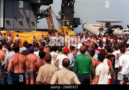 Des membres de l'équipage à bord du porte-avions à propulsion nucléaire USS THEODORE ROOSEVELT (CVN-71) se rassemblent sur le pont de vol pour observer une danseuse à bord pour le « pique-nique sur la plage » du navire à la suite de l'opération Desert Storm. Le ROOSEVELT est ancré à environ 13 kilomètres de la côte de Bahreïn. Sujet opération/série: TEMPÊTE DANS LE DÉSERT pays: Inconnu Banque D'Images