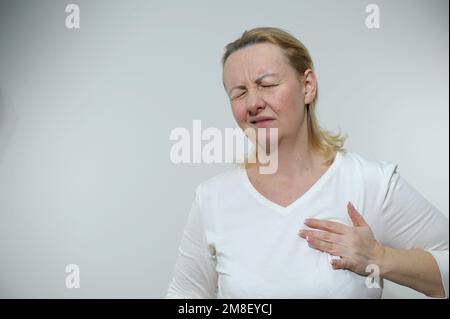 des douleurs cardiaques de femme adulte elle a mis la main à la poitrine elle est fatiguée elle n'a pas de coiffure pas de maquillage travail dur sans vie de repos sans voyage elle a corrigé la bouche et fermé les yeux espace pour le texte de la maladie fatiguée Banque D'Images