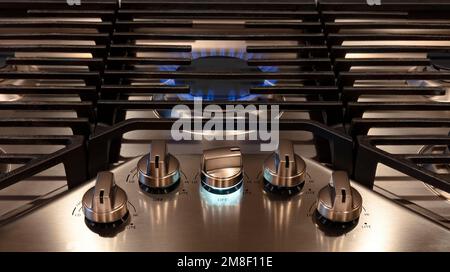 Cuisine moderne cuisinière avec boutons de commande et grils métalliques. Flamme de gaz gros plan sur un brûleur de cuisinière à gaz naturel avec grill en métal Banque D'Images