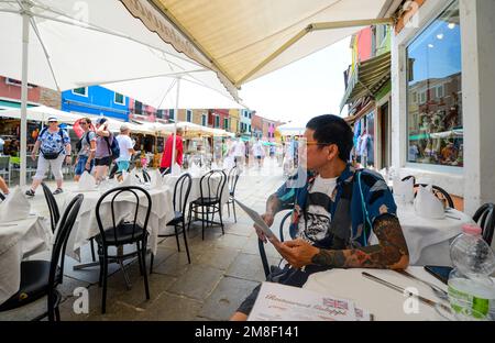 ÎLE DE BURANO, VENISE, ITALIE - 4 JUILLET 2022 : touristes parmi les boutiques et restaurants souverains de la rue principale de l'île de burano, maisons colorées Banque D'Images