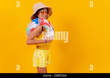 Portrait d'une fille avec un flotteur pendant les vacances d'été sur fond jaune, portant des lunettes de soleil Banque D'Images