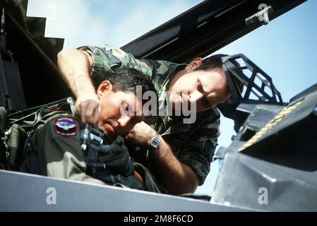 En préparation pour le vol de retour après l'opération Desert Storm, le PERSONNEL en chef de l'équipage du F-117 Stealth Fighter Aircraft SGT. David Owings aide le Maj pilote. Joe Bowley de l'aile tactique de 37th s'installe dans le poste de pilotage. Objet opération/série : REDÉPLOIEMENT D'UNE TEMPÊTE DANS LE DÉSERT pays : Arabie saoudite (SAU) Banque D'Images