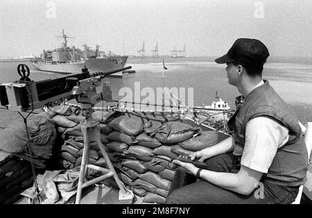 Un membre de l'équipage à bord du navire de commandement amphibie USS BLUE RIDGE (LCC-19) est assis à côté d'une mitrailleuse de calibre M-2 .50 alors qu'il observe l'arrivée du navire des magasins de combat USS NIAGARA FALLS (AFS-3) dans le port. Les deux États-Unis Des navires de la Marine ont été déployés dans le golfe Persique au cours des opérations Bouclier du désert/tempête du désert. Une mitrailleuse de calibre M-2 .50 à bord de la BLUE RIDGE est au premier plan. Sujet opération/série: BOUCLIER DU DÉSERT TEMPÊTE DU DÉSERT base: Manama pays: Bahreïn(BHR) Banque D'Images