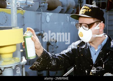 Un marin porte un respirateur et des lunettes de sécurité tout en pulvérisant un accessoire à bord du croiseur à missiles guidé USS HARRY E. YARNELL (CG-17). Base: Naval Air Station, Norfolk État: Virginie (va) pays: Etats-Unis d'Amérique (USA) Banque D'Images