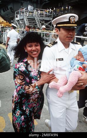 Un officier du porte-avions USS AMERICA (CV-66) est réuni avec sa famille après l'arrivée du navire au port. L'AMÉRIQUE vient de rentrer à Norfolk à la suite d'un déploiement dans la région du golfe Persique au cours de l'opération tempête du désert. Objet opération/série: TEMPÊTE DU DÉSERT base: Naval Air Station, Norfolk État: Virginie (va) pays: États-Unis d'Amérique (USA) Banque D'Images