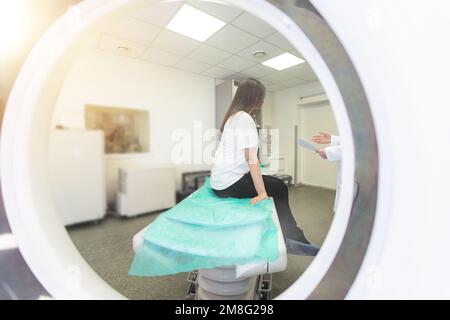 Un technologue en acquisition CT qui regarde le patient dans le scanner de tomodensitométrie pendant la préparation de la procédure. Femme entrant dans le scanner CT. Banque D'Images