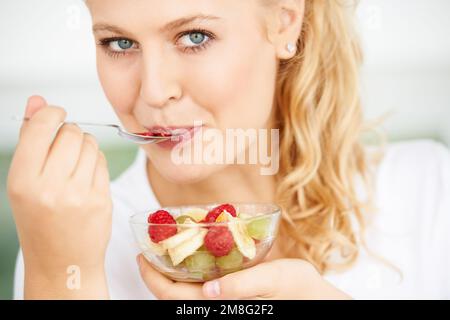Une bonne santé commence par une bonne alimentation. Gros plan d'une jeune femme attrayante mangeant une salade de fruits. Banque D'Images